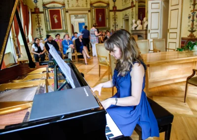 Pianistin spielt bei standesamtlicher Hochzeit in Schloss Ismaning, Gäste im Hintergrund, Hochzeitsfoto nördlich von München.