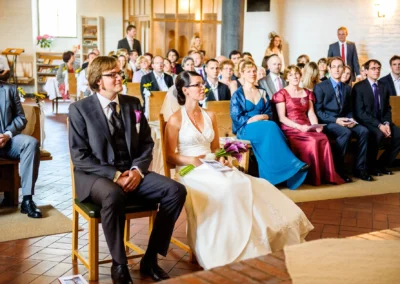 Brautpaar und Gäste sitzen bei der kirchlichen Trauung in der Friedenskirche Dachau, Hochzeitsfoto.