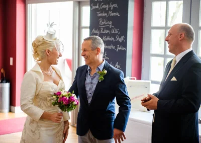 Brautpaar und Gast lachen bei standesamtlicher Trauung in Bad Toelz, festgehalten von Hochzeitsfotograf.