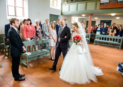 Braut schreitet mit Blumenstrauss zum Altar in der Kirche. Hochzeitsfoto in Sankt Nikolaus Schalkhausen-Ansbach.