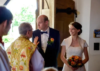 Brautpaar mit Priester bei Trauung in St. Johann-Baptist Irschenberg, Teil der Hochzeitsfotografie.