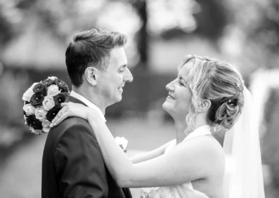 Brautpaar lachend im Hofgarten Muenchen, Braut mit Blumenstrauss. Hochzeitsfotografie im Freien, romantische Szene.