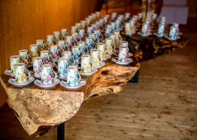 Blumige Teetassen arrangiert auf rustikalem Holztisch bei einer Hochzeitsreportage in Otterfing.