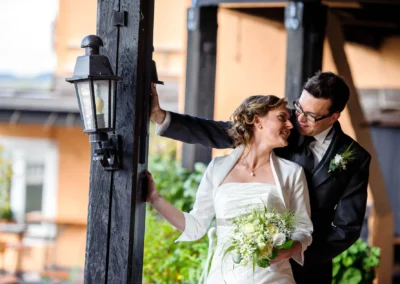 Brautpaar laechelt sich an, Hochzeitsfoto am Starnberger See, Braut mit Blumenstrauss, aufgenommene Hochzeitsportraits.