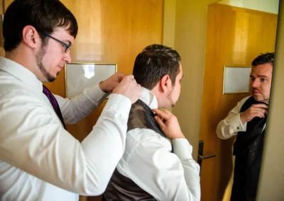 Mann hilft Bräutigam beim Ankleiden vor Spiegel, Hochzeit nahe Dillingen. Hochzeitsvorbereitung festgehalten.