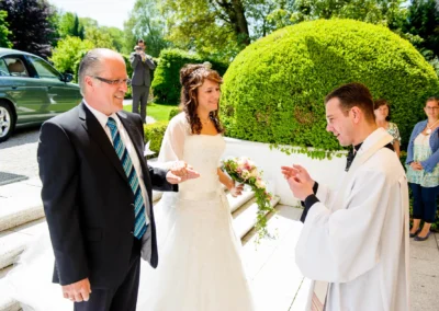 Brautpaar und Geistlicher bei kirchlicher Trauung im Schloss Aufhausen nahe Muenchen, festgehalten in Hochzeitsreportage.