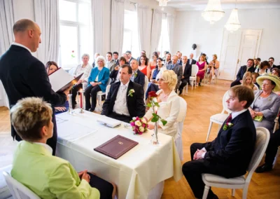 Standesamtliche Trauung in Bad Toelz, Gaeste sitzen im Raum, Brautpaar vorne am Tisch, Hochzeitsfotografie.
