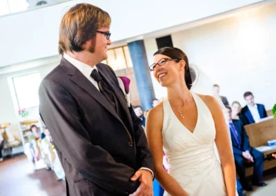 Brautpaar bei kirchlicher Trauung in Dachau, Braut in weißem Kleid, Bräutigam im Anzug, lächelnd einander zugewandt.