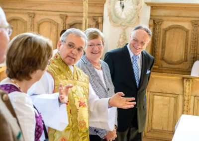 Kirchliche Trauung in St. Johann-Baptist Irschenberg, der Priester spricht mit Hochzeitsgaesten. Hochzeitsreportage.