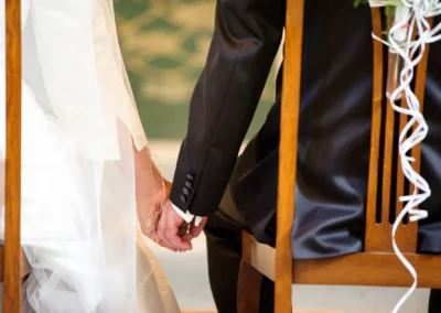 Braut und Bräutigam halten bei einer Hochzeitsreportage in einer Kirche bei München Hände.