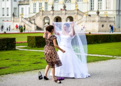 Braut spielt mit Schleier im Garten von Schloss Nymphenburg, Hochzeitsfotografie Muenchen.