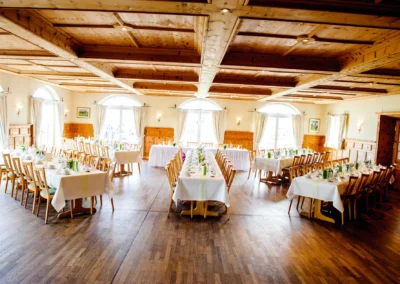 Elegantes Hochzeitsfoto: Dekorierte Tische in Aschbacher Hof, mit weissen Tischdecken und Holzstuehlen.