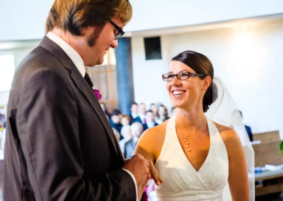 Brautpaar bei kirchlicher Trauung in Friedenskirche Dachau, lächelnd und Hand haltend, Hochzeitsfotografie.