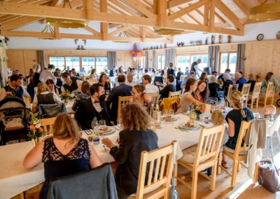 Hochzeitsfeier in einem rustikalen Saal bei Otterfing, Gaeste essen und unterhalten sich, Hochzeitsfotografie.