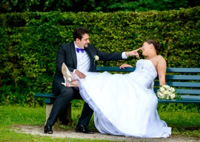 Brautpaar lacht auf einer Bank im Park. Hochzeitsportrait aus Muenchen Nymphenburg mit Brautstrauss.