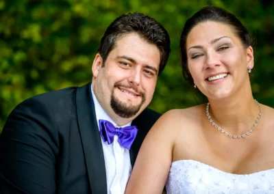 Brautpaar laechelt bei Hochzeitsfotografie im Freien, aufgenommen in Muenchen Nymphenburg.