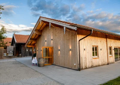 Holzgebäude bei Hochzeit am Archehof Schlickenrieder in Otterfing, mit rustikalem Charme und abendlicher Beleuchtung.