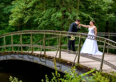 Brautpaar auf Bruecke im Gruenen bei einer Hochzeitsreportage in Schloss Nymphenburg, romantische Hochzeitsfotografie.