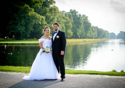 Brautpaar beim Hochzeitsfoto am Wasser im Schloss Nymphenburg, München, festgehalten von Hochzeitsfotograf.