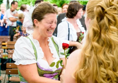 Frau im Dirndl lacht bei einer Hochzeit in Rohrmoos, im Hintergrund Gaeste. Hochzeitsfotograf aus Muenchen.