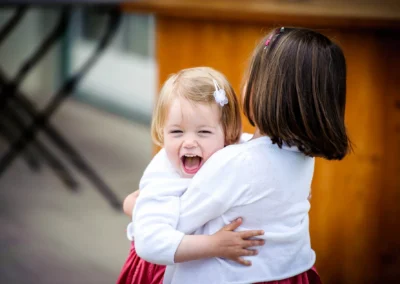 Zwei Kinder umarmen sich lachend bei einer Hochzeit im Aschbacher Hof, festgehalten in einer Hochzeitsreportage.