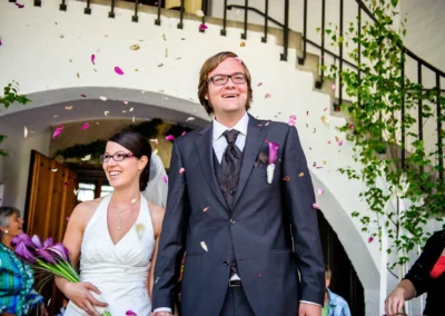 Brautpaar laechelt bei kirchlicher Trauung in der Friedenskirche Dachau, umgeben von fallenden Bluetenblaettern.