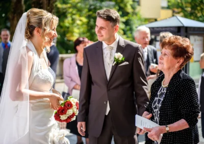 Brautpaar im Freien bei kirchlicher Trauung in Muenchen Schwabing, Hochzeitsreportage von lachenden Gaesten begleitet.