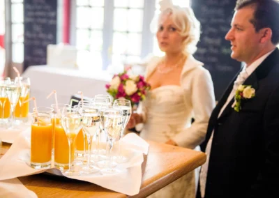 Brautpaar neben einem Tisch mit Saft und Sekt, Hochzeitsfotograf Oberbayern, Bild einer Hochzeitsfeier.