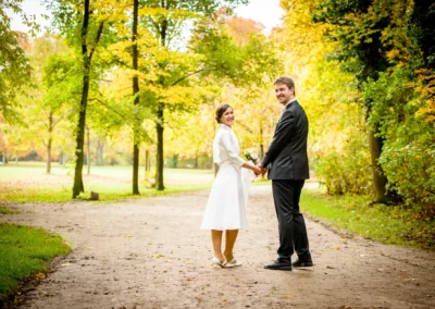 Brautpaar spaziert Hand in Hand im englischen Garten München bei einer Hochzeitsreportage.