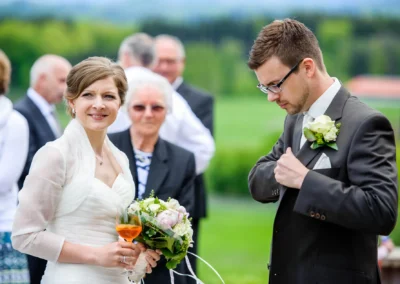 Braut und Bräutigam bei Hochzeitsfeier im Freien, Aschbacher Hof, mit Gästen im Hintergrund. Hochzeit im Grünen.