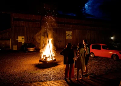 Gäste um ein Feuer bei einer Hochzeit in Otterfing, festgehalten von einem Hochzeitsfotografen bei Holzkirchen.