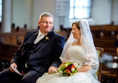 Brautpaar laechelt einander an in Kirche St. Lukas Muenchen bei kirchlicher Trauung, festgehalten in Hochzeitsfoto.