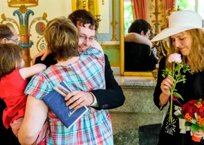 Hochzeitsfoto: Ein Mann umarmt eine Frau mit Kind, daneben eine Frau mit Blumen, Ismaning. Emotionale Hochzeitsreportage.