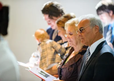 Gäste bei kirchlicher Trauung in München, fokussiert auf die Hochzeitsdetails in ihren Händen.