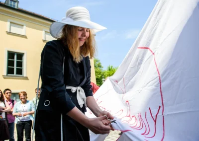 Frau beim Ausschneiden eines großen Tuchs bei einer Hochzeit nördlich von München. Zuschauer im Hintergrund.