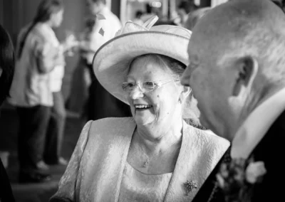 Ältere Frau lacht bei einer Hochzeit in suedlich Muenchen, elegant gekleidet mit Hut, Hochzeitsreportage.