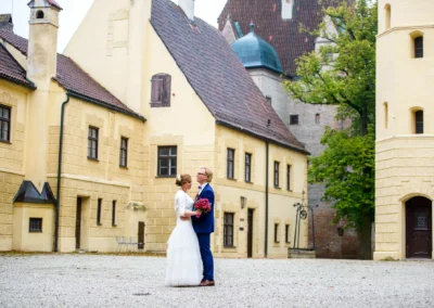 Brautpaar-Portrait vor gelbem Gebaeude bei einer Hochzeitsreportage auf der Burg Trausnitz.