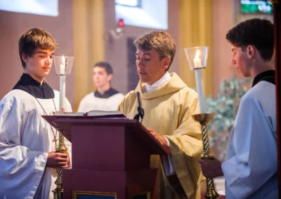 Priester und Ministranten bei kirchlicher Trauung in Muenchen mit Kerzenstaendern und Rednerpult, Teil der Hochzeitsfotografie.