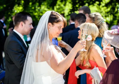 Braut hebt Sektglas unter Gaesten bei einer Hochzeitsreportage in Gauting nahe Muenchen. Feierliche Stimmung.