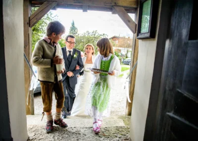 Brautpaar beim Betreten der Kirche begleitet von Kindern in Tracht, aufgenommen bei einer Hochzeit in Starnberg.