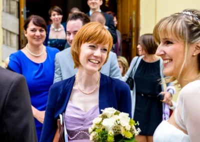 Braut und Gaeste lachen bei kirchlicher Trauung in Neuburg an der Donau, festgehalten in Hochzeitsreportage.