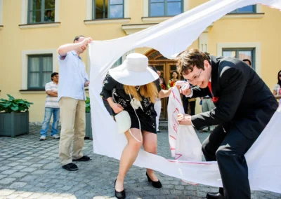 Brautpaar durchschneidet Laken bei Hochzeit nördlich von München, Gäste schauen zu. Hochzeitsreportage.