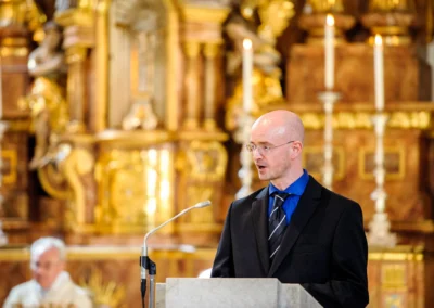 Mann in Anzug spricht bei kirchlicher Trauung, Sankt Sylvester Muenchen. Hochzeitsreportage von Hochzeitsfotograf.