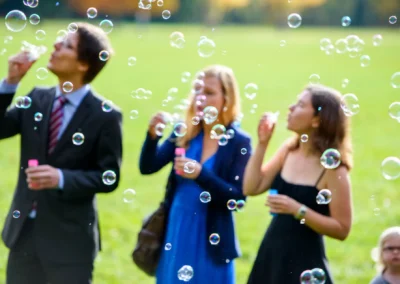 Personen machen Seifenblasen bei einer Hochzeit im Englischen Garten München. Festliche Momente im Freien.