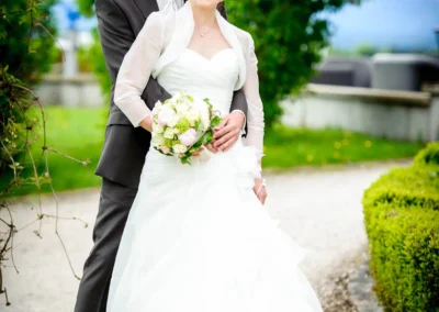 Brautpaar bei ihrer Hochzeit im Aschbacher Hof, posiert lächelnd auf einem Gartenweg, Hochzeitsfotografie.