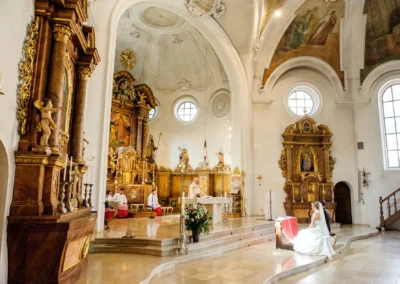 Brautpaar bei kirchlicher Trauung in sankt sylvester muenchen. Hochzeitsreportage mit goldenen Altaren und Verzierungen.