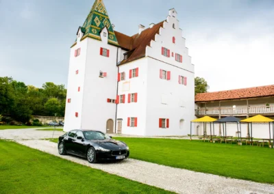 Schwarzes Auto vor Schloss Gruenau, Hochzeitsfotografie, nahe Neuburg an der Donau, gruene Wiese, historische Architektur.