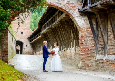 Brautpaar bei Hochzeitsfotografie in Landshut, posiert unter historischem Torbogen aus rotem Backstein.