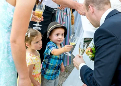Kinder und Erwachsene stoßen bei einer Hochzeit in Irschenberg mit Sekt an. Hochzeitsfotografie vom Hochzeitsfotografen.