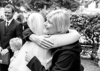 Braut umarmt Gast bei Hochzeit in Muenchen-Lehel, freudiger Moment festgehalten von Hochzeitsfotograf.